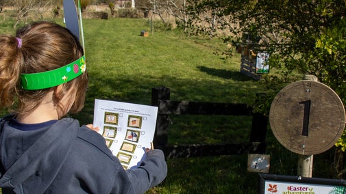 A girl wearing bunny ears following the Easter trail in the orchard at Horsey Windpump